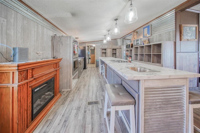 kitchen featuring decorative light fixtures, a kitchen bar, wooden walls, and a textured ceiling