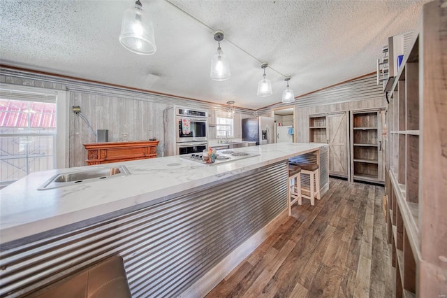 kitchen with crown molding, dark hardwood / wood-style floors, stainless steel appliances, and hanging light fixtures