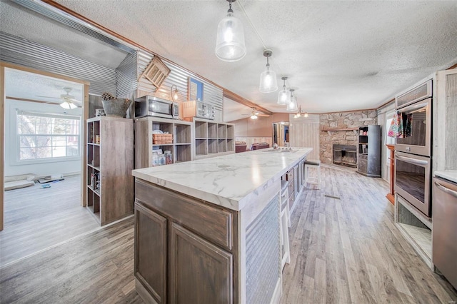 kitchen featuring decorative light fixtures, light hardwood / wood-style flooring, a textured ceiling, and a center island