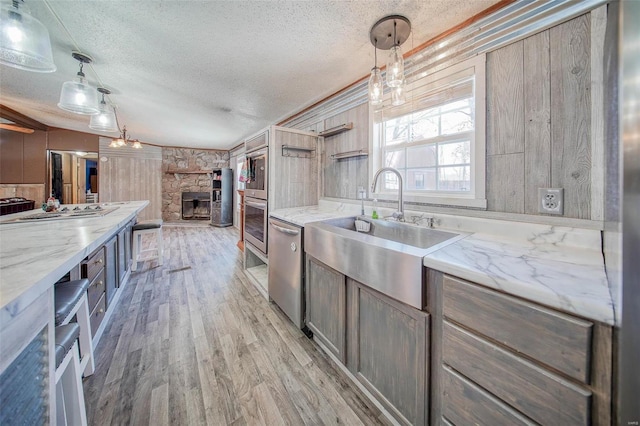 kitchen featuring decorative light fixtures, sink, light stone countertops, appliances with stainless steel finishes, and a textured ceiling