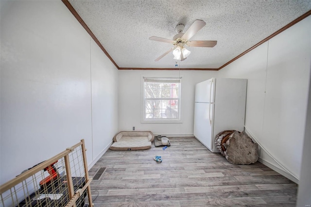 interior space with ceiling fan, crown molding, a textured ceiling, and light hardwood / wood-style flooring