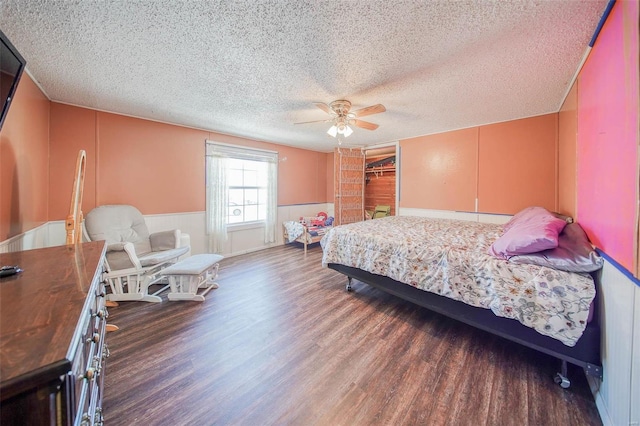 bedroom featuring ceiling fan, dark wood-type flooring, a closet, a textured ceiling, and a walk in closet