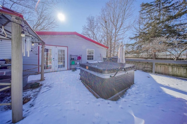 snow covered deck with french doors and a hot tub