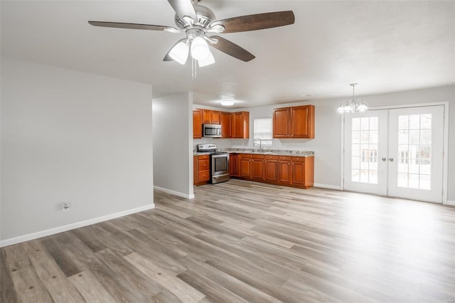 kitchen with french doors, ceiling fan with notable chandelier, stainless steel appliances, sink, and decorative light fixtures