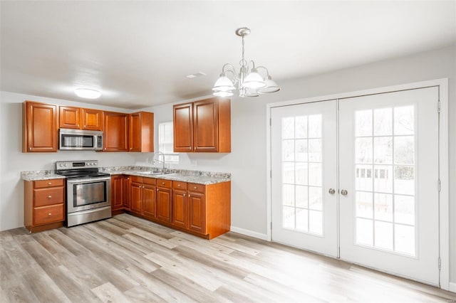 kitchen with sink, light stone counters, a notable chandelier, pendant lighting, and appliances with stainless steel finishes