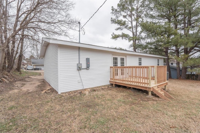 rear view of house featuring french doors, a lawn, and a wooden deck