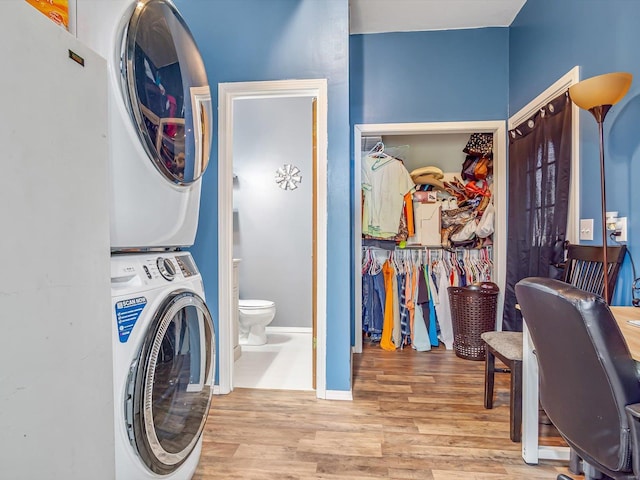 clothes washing area with stacked washer / drying machine and light hardwood / wood-style floors