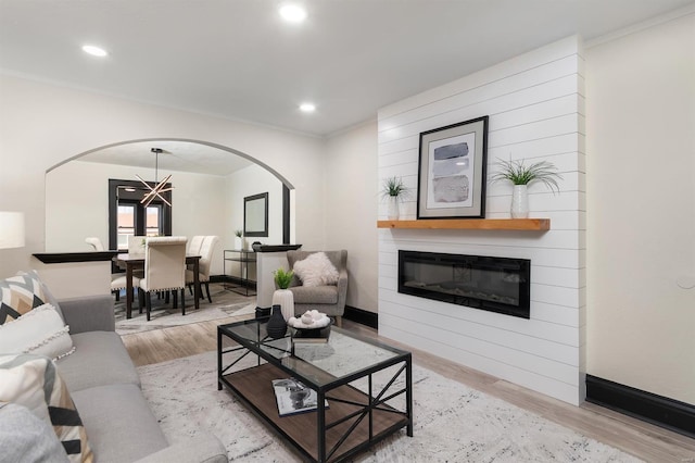 living room with a fireplace, ornamental molding, and light hardwood / wood-style flooring