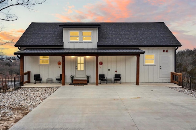 back house at dusk featuring covered porch