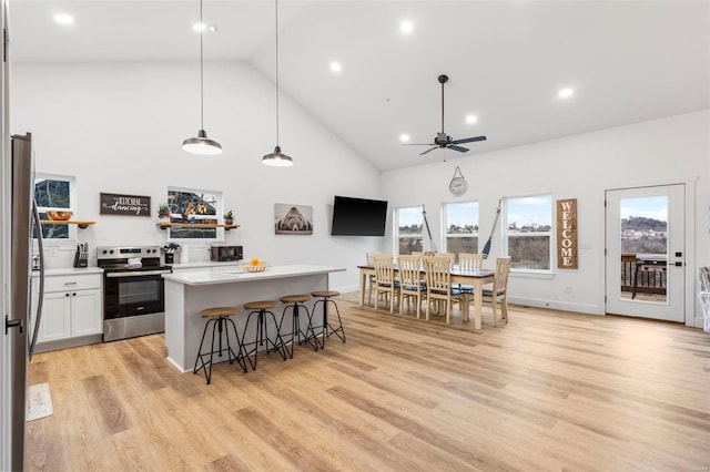 kitchen with appliances with stainless steel finishes, ceiling fan, high vaulted ceiling, white cabinets, and hanging light fixtures