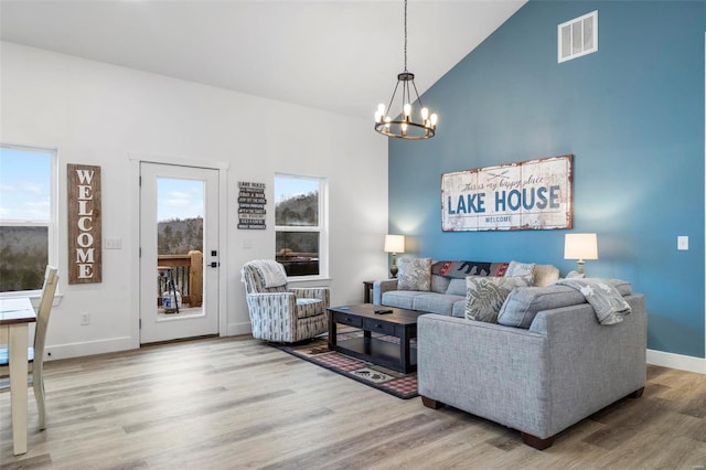 living room with hardwood / wood-style floors, high vaulted ceiling, and an inviting chandelier