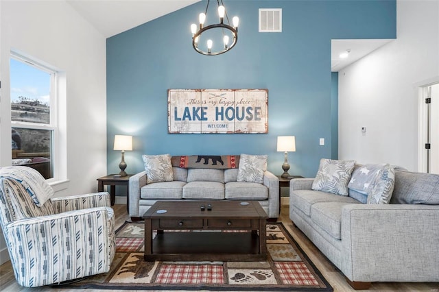 living room with hardwood / wood-style flooring, a notable chandelier, and lofted ceiling