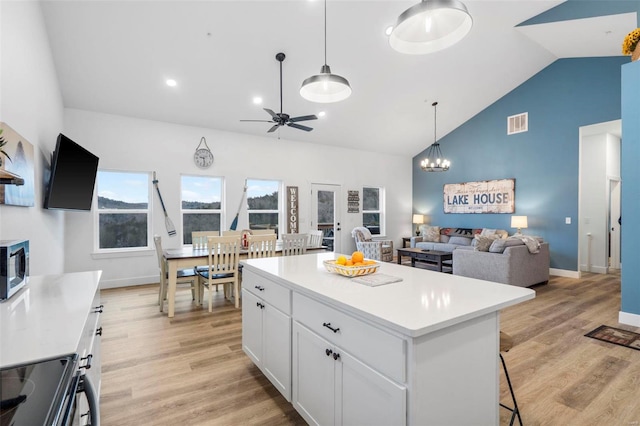 kitchen featuring a kitchen island, a kitchen bar, white cabinetry, and light hardwood / wood-style flooring