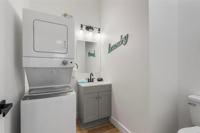 laundry area featuring sink, stacked washer and dryer, and dark wood-type flooring