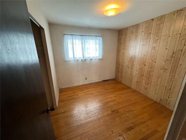 unfurnished bedroom with wood walls and light hardwood / wood-style floors