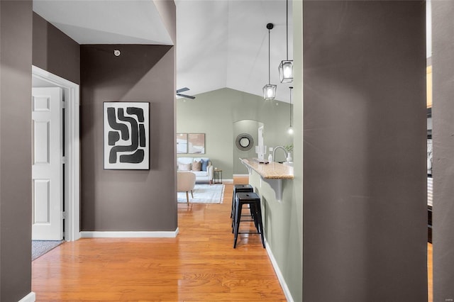 corridor with wood-type flooring, vaulted ceiling, and sink