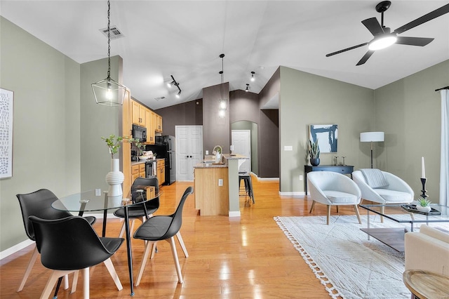 dining area with ceiling fan, lofted ceiling, and light hardwood / wood-style flooring