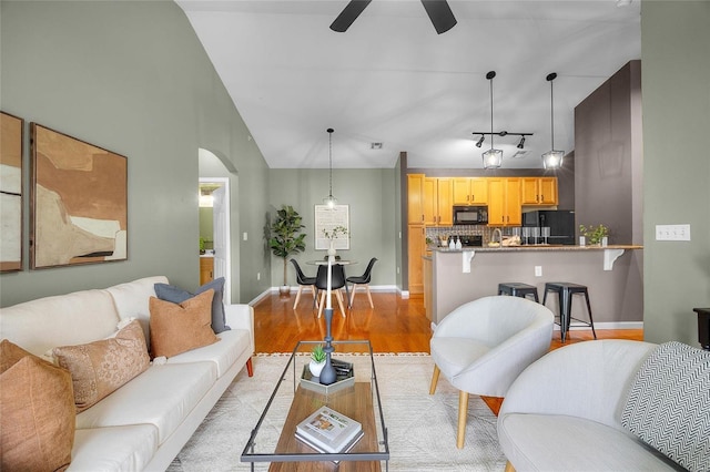 living room featuring ceiling fan, light wood-type flooring, and lofted ceiling