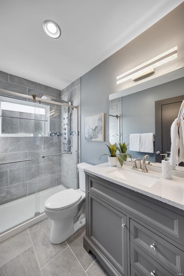 bathroom featuring a shower with door, tile patterned floors, toilet, and vanity