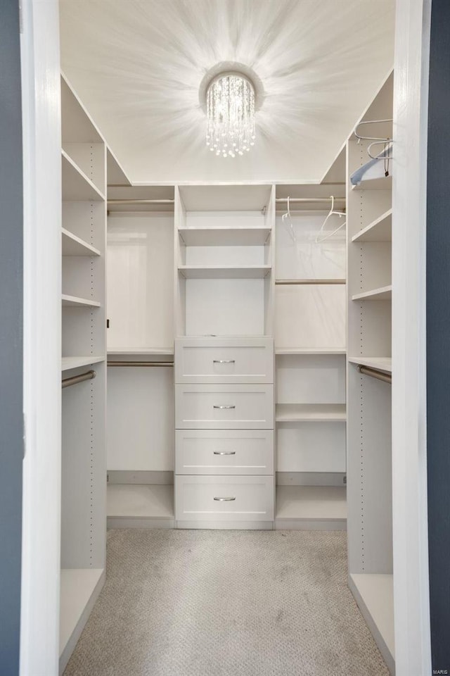 spacious closet featuring light colored carpet and a notable chandelier