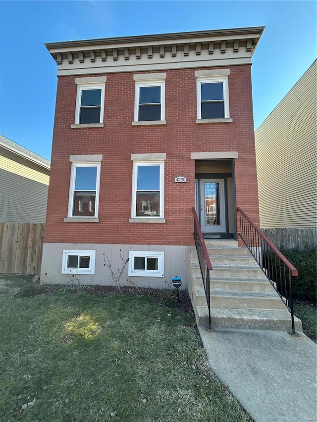 view of front of home with a front yard, fence, and brick siding