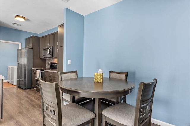 dining space featuring separate washer and dryer and light hardwood / wood-style flooring