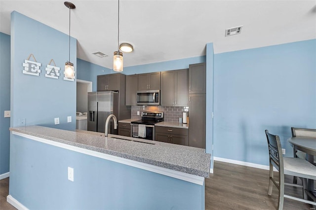 kitchen with kitchen peninsula, backsplash, stainless steel appliances, and washing machine and clothes dryer