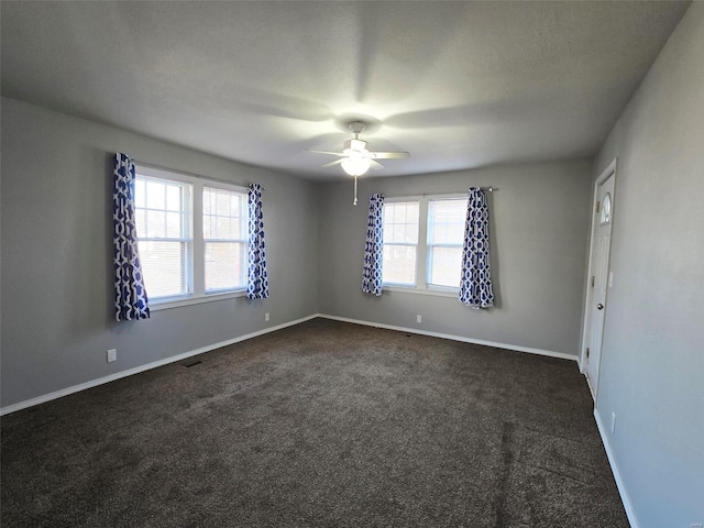 spare room with ceiling fan and dark carpet