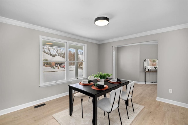 dining area with light hardwood / wood-style flooring and crown molding