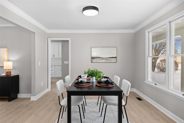 dining area featuring a wealth of natural light, crown molding, and light hardwood / wood-style floors