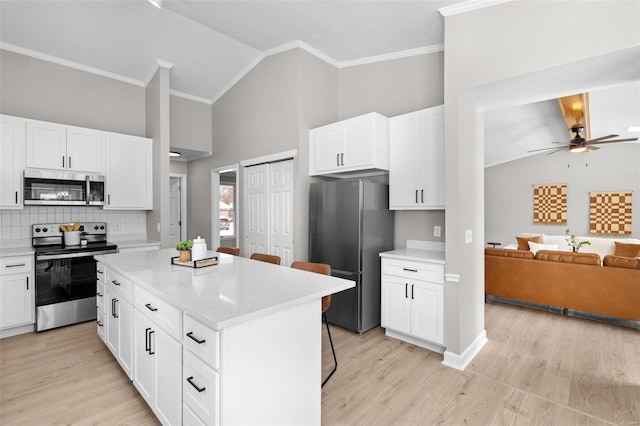 kitchen featuring a kitchen breakfast bar, white cabinetry, a kitchen island, and stainless steel appliances