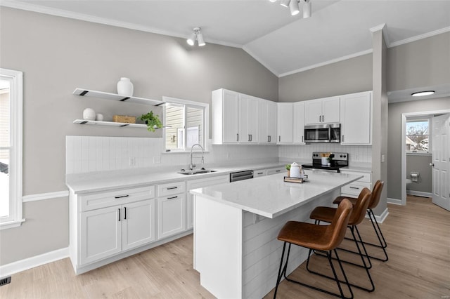 kitchen featuring white cabinetry, a center island, sink, vaulted ceiling, and appliances with stainless steel finishes