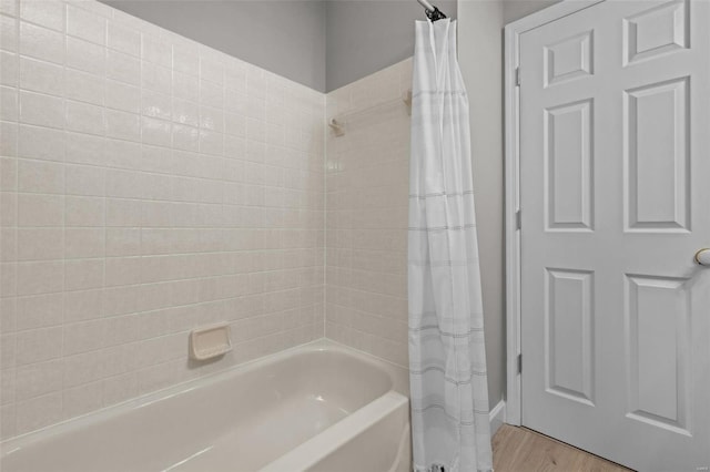 bathroom with hardwood / wood-style flooring and shower / tub combo with curtain