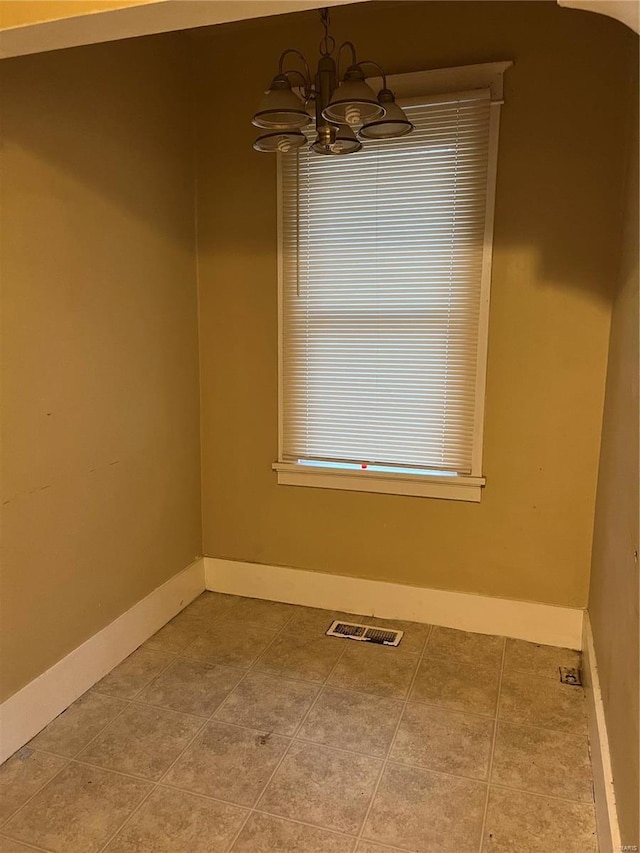 tiled empty room with a chandelier