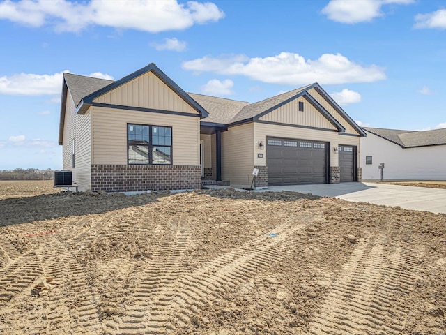 view of front of home with brick siding, board and batten siding, central air condition unit, driveway, and an attached garage