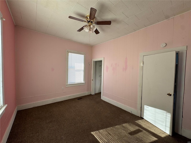 unfurnished bedroom with dark carpet and ceiling fan