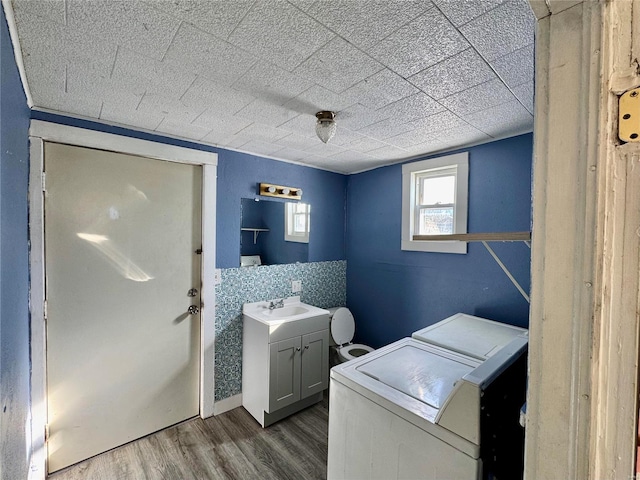 laundry area with hardwood / wood-style floors, washer and dryer, cabinets, and sink