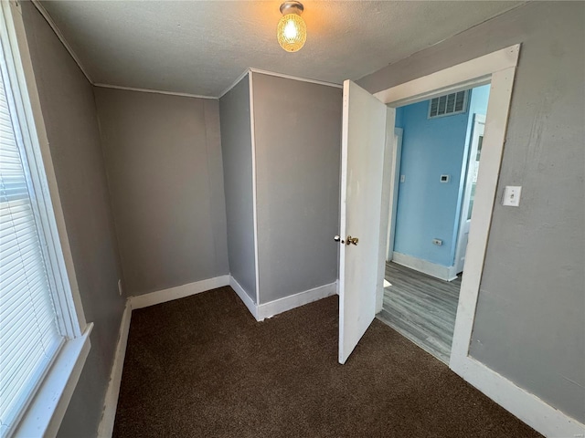 bonus room featuring a textured ceiling and dark carpet