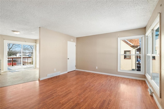 empty room with hardwood / wood-style floors and a textured ceiling