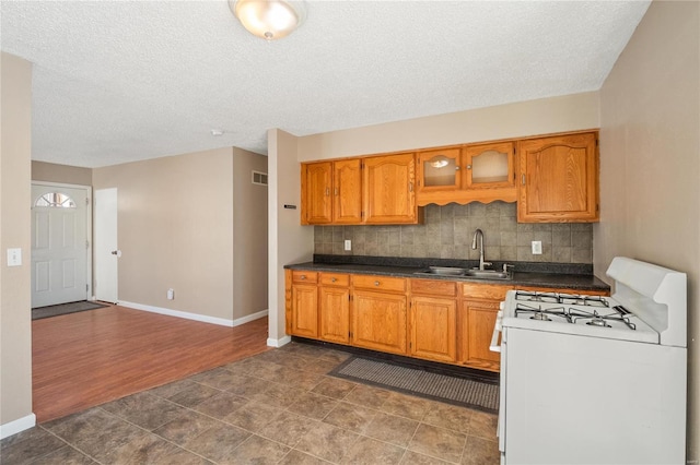 kitchen with tasteful backsplash, sink, white range with gas stovetop, and a textured ceiling