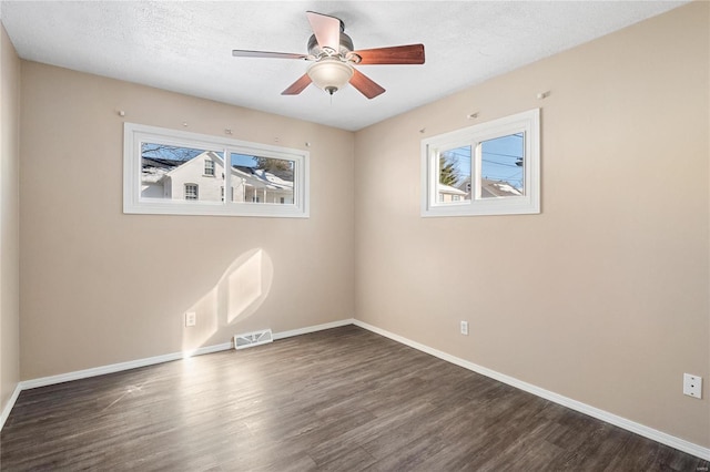 spare room with ceiling fan, dark hardwood / wood-style floors, a wealth of natural light, and a textured ceiling