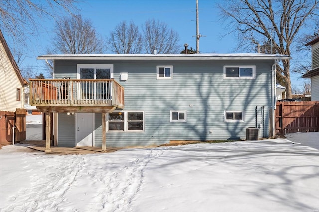 snow covered rear of property featuring central AC and a deck