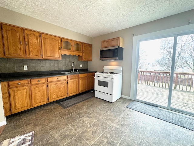 kitchen featuring white gas range, decorative backsplash, sink, and a textured ceiling