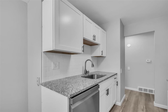 kitchen with light stone counters, sink, white cabinets, and stainless steel dishwasher