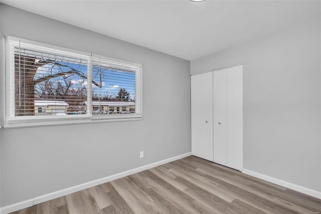 unfurnished bedroom featuring multiple windows, wood-type flooring, and a closet