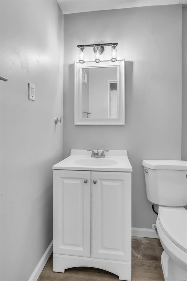 bathroom with wood-type flooring, vanity, and toilet