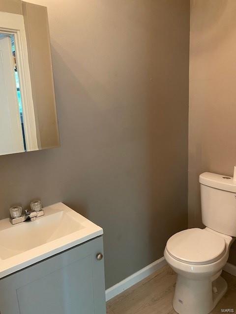 bathroom with hardwood / wood-style floors, vanity, and toilet