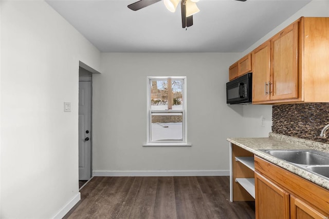 kitchen featuring backsplash, sink, ceiling fan, light stone counters, and dark hardwood / wood-style flooring