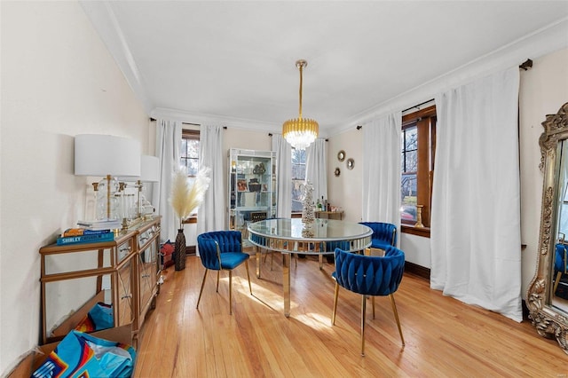 dining area with an inviting chandelier, light hardwood / wood-style flooring, and ornamental molding