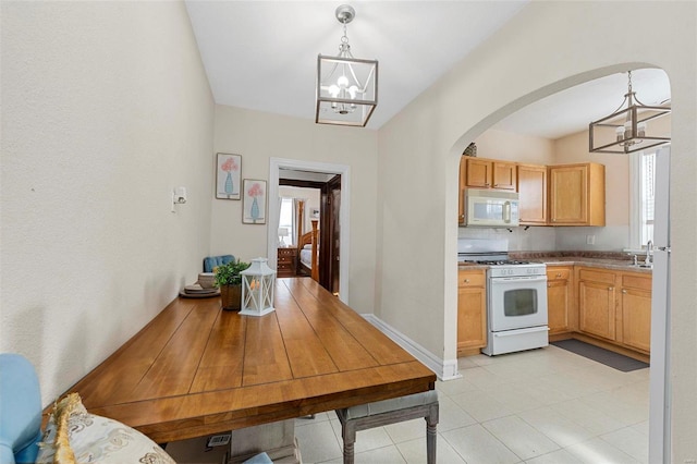 kitchen featuring a chandelier, light brown cabinetry, hanging light fixtures, and white appliances